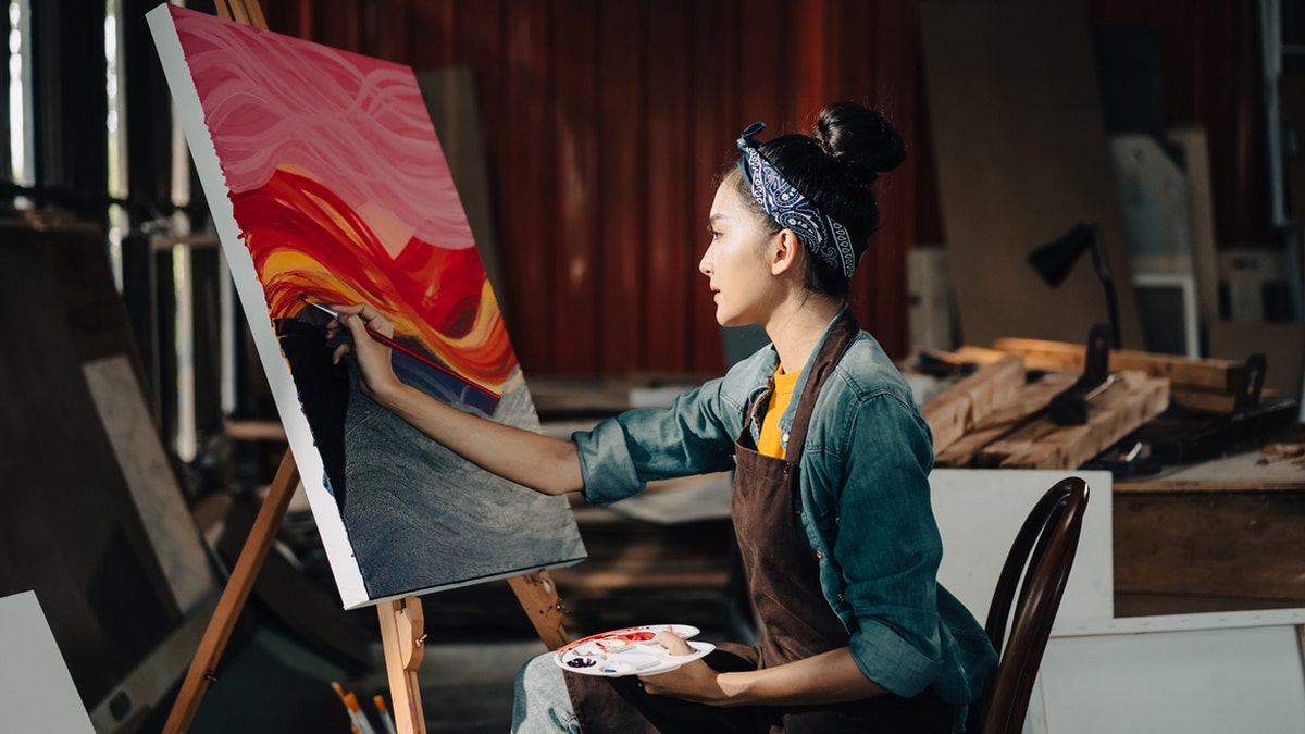 An artist painting on a large canvas